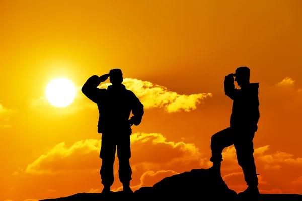 Silhueta tiro de soldado segurando arma com céu colorido e montanha no fundo — Fotografia de Stock