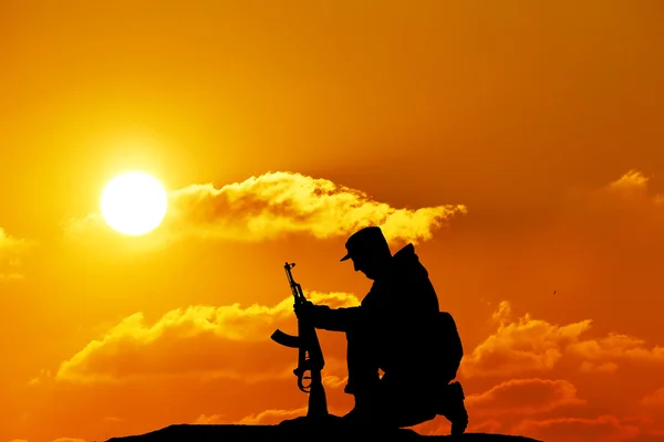 Silhouet schot van soldaat met pistool met kleurrijke hemel en berg op de achtergrond — Stockfoto