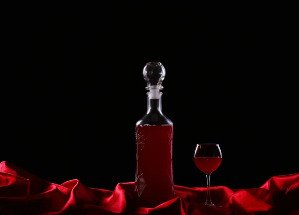 Стакан и бутылка вина на темном фоне шелка — стоковое фото
