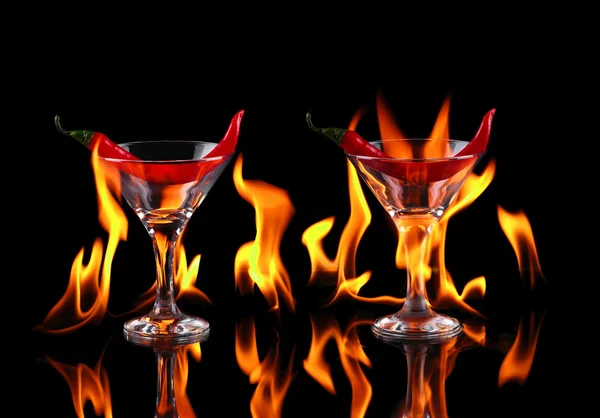 Pimienta picante en una copa de martini con un fuego en un respaldo negro —  Fotos de Stock