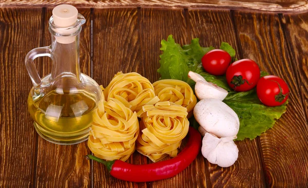 Pasta on the wooden background with tomato, pepper, olive oil, m — Stock Photo, Image
