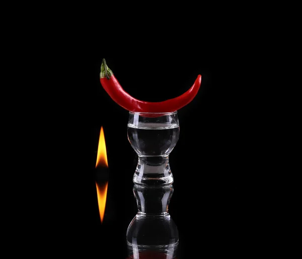 Hot chili pepper in a shot  glass with a fire on a black background — Stock Photo, Image