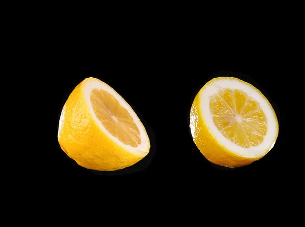 Estudio de rodajas y limones enteros sobre fondo negro — Foto de Stock