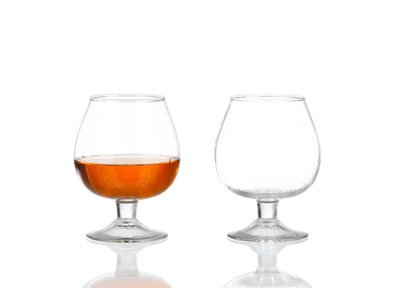 Dvě sklenky brandy (prázdné a s alkoholem) izolované na bílém pozadí — Stock fotografie