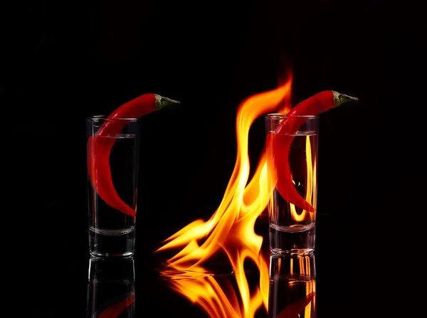 Scharfe Chilischote im Schnapsglas mit Feuer auf schwarzem Backgro — Stockfoto