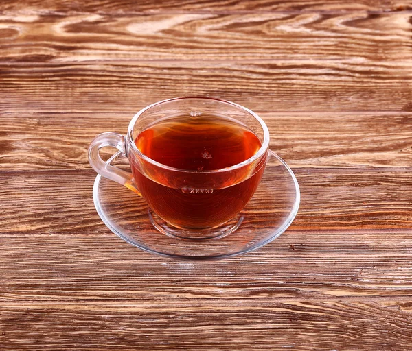 Скляна чашка чаю на дерев'яному столі з листям монетного двору . — стокове фото