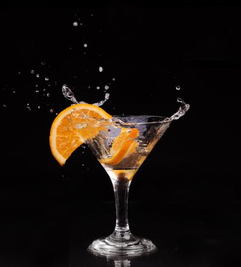 dilim limon bir bardak su ile bir sprey su damlacıkları koyu arka plan üzerinde cam üzerindeki hava içinde hareket içine sıçramasına.