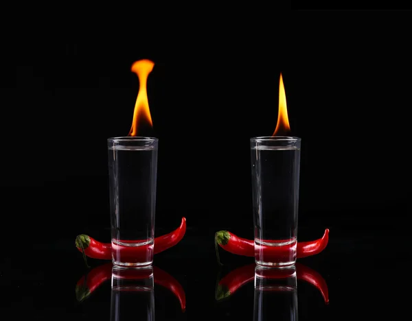 Collage Pimienta picante en un vaso de chupito con fuego sobre fondo negro — Foto de Stock