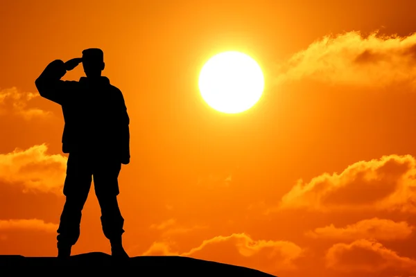 Silhouette shot of soldier holding gun with colorful sky and mountain in background — Stock Photo, Image
