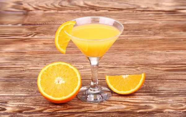 Verre de jus d'orange fraîchement pressé avec moitié d'orange tranchée sur une table en bois — Photo