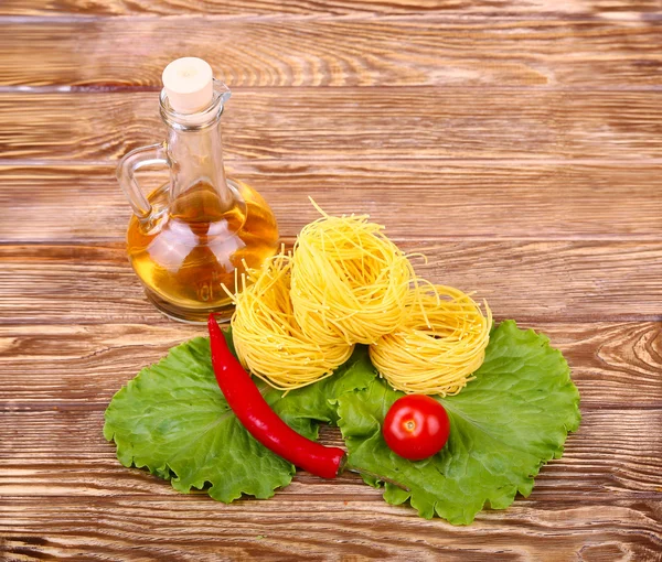 Pâtes sur fond de bois avec tomate, laitue, huile d'olive et poivre — Photo