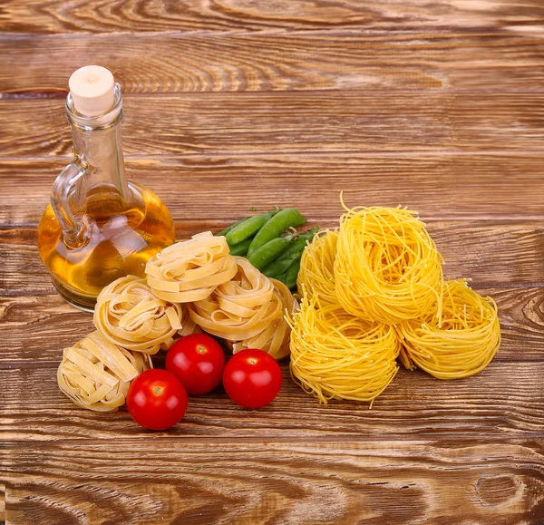 Paste pe fundal din lemn cu roșii, salată verde piper, ulei de măsline și piper. — Fotografie, imagine de stoc