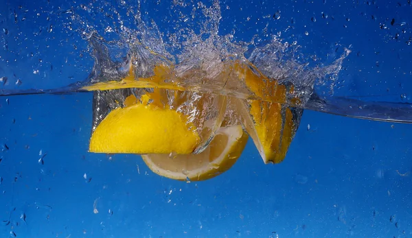 Collage hele citroen daalde in water tegen blauwe achtergrond met kleurovergang — Stockfoto