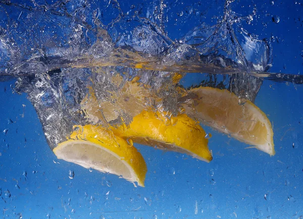 Collage hela citron tappade i vatten mot tonad blå bakgrund — Stockfoto