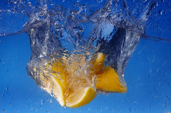Collage hele citroen daalde in water tegen blauwe achtergrond met kleurovergang — Stockfoto