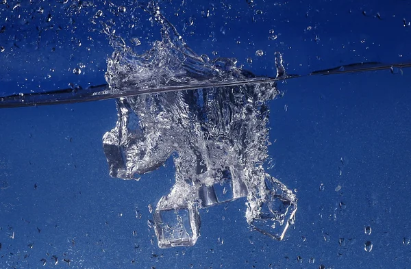Ijsblokjes spatten in water, close-up — Stockfoto