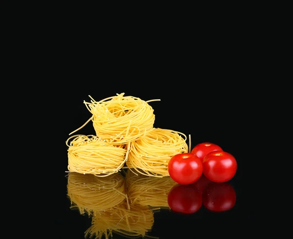 Pasta cruda a nido secco con riflesso sul nero con pomodoro — Foto Stock