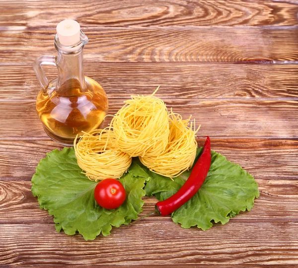 Паста на деревянном фоне с помидорами, салатным перцем, оливковым маслом и перцем — стоковое фото