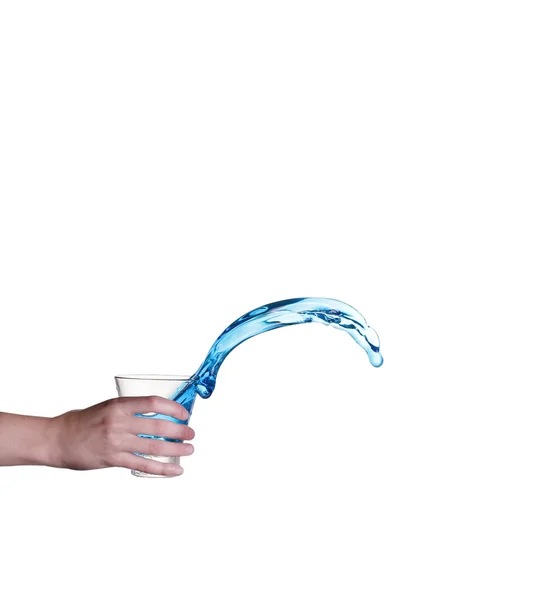 Salpicaduras de agua azul en vidrio sostenido a mano, fondo blanco — Foto de Stock