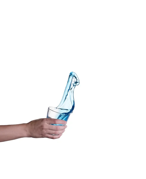 Salpicaduras de agua azul en vidrio sostenido a mano, fondo blanco — Foto de Stock