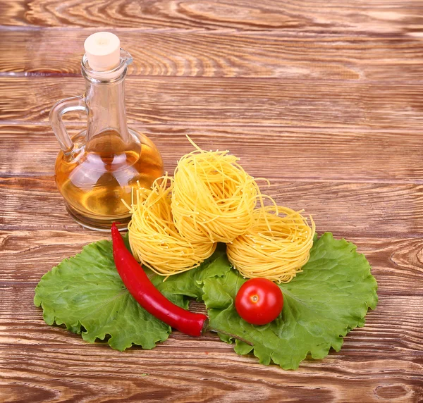 Pâtes sur fond de bois avec tomate, laitue, huile d'olive et poivre — Photo