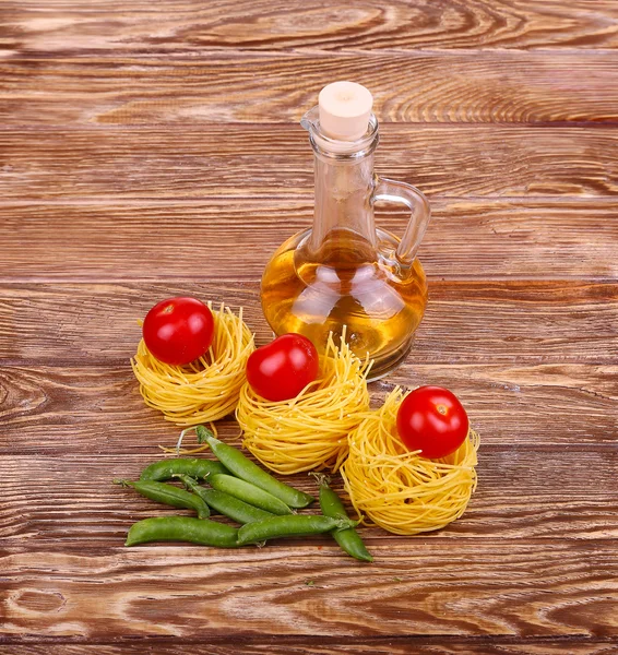 Pâtes sur fond de bois avec tomate, laitue, huile d'olive et poivre. — Photo