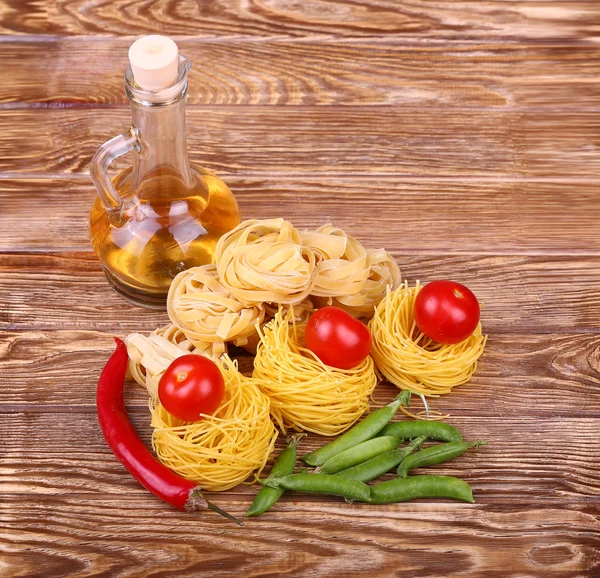 Паста на деревянном фоне с помидорами, перцем летучий, оливковым маслом и перцем. — стоковое фото