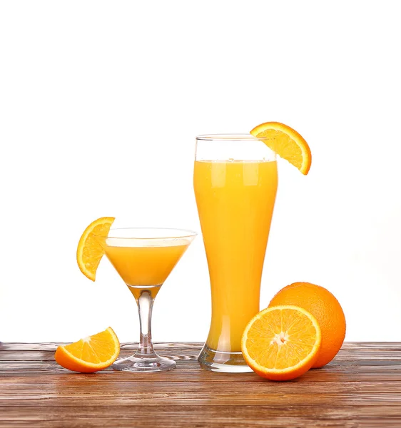 Verre de jus d'orange fraîchement pressé avec moitié d'orange tranchée sur une table en bois — Photo