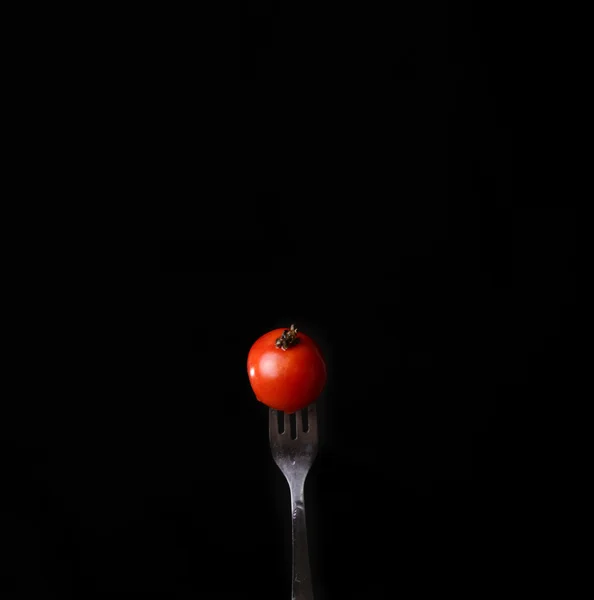 Tomate auf einer Gabel schwarzen Hintergrund — Stockfoto