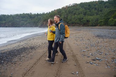 Çiftler Türk kıyı şeridini seviyor. Taşlarda oturmak, deniz dalgalarını izlemek, birlikte dinlenmek, sakin mavi suyun yanında, yumuşak kış ışığı altında romantik bir an..
