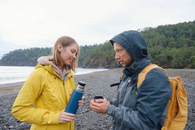 Çiftler Türk kıyı şeridini seviyor. Taşlarda oturmak, deniz dalgalarını izlemek, birlikte dinlenmek, sakin mavi suyun yanında, yumuşak kış ışığı altında romantik bir an..