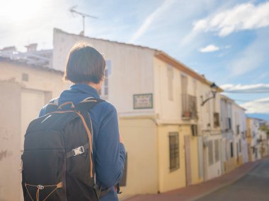 İspanya 'nın Alicante eyaletinin büyüleyici dar sokaklarında gezinen, tarihi Akdeniz mimarisi ile çevrili, barışçıl atmosfer ve kültürel ortamın tadını çıkaran genç bir kadın..