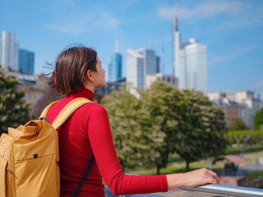 Turist kadın modern Frankfurt 'u keşfediyor, çağdaş mimari, gökdelenler ve kentsel alanlarla hareketli caddelerde yürüyor, modern yan tarafların canlı atmosferinin tadını çıkarıyor..