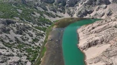 Obrovac 'tan nehir ağzı antenine kadar Zrmanja kanyonu nehri. Dolambaçlı Zrmanja nehrinin havadan çekimleri derin kanyonu, bereketli bahar renklerini ve uzak yolları kesiyor.