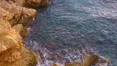 Cala Tio Ximo kıyı şeridi Aralık akşamında ele geçirildi. Sakin kış denizi, yumuşak gün batımı parıltısı, Benidorm yakınlarındaki küçük adanın huzurlu manzarası. Sessiz doğal güzellik, insan yok, sadece deniz ve gökyüzü..