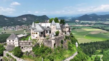 Tepedeki Hochosterwitz Kalesi 'ni, güçlendirilmiş duvarları, dramatik uçurumları, yaz renklerini, silip süpüren hava hareketlerini, tarihi dönüm noktalarını görüntüleyen sinematik dron görüntüleri.