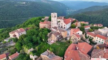 Yaz boyunca Hırvatistan 'ın Istria kentindeki Oprtalj tepesindeki ortaçağ kasabasının hava aracı görüntüleri. Tarihi taş evler, dar sokaklar, çevre tepeler ve otantik Avrupa manzarası.
