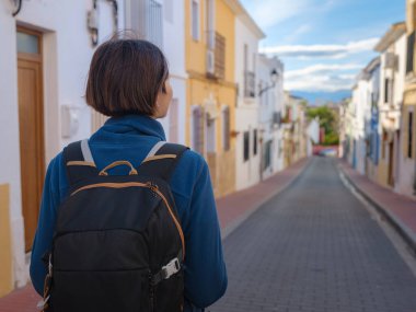 İspanya 'nın Alicante eyaletinin büyüleyici dar sokaklarında gezinen, tarihi Akdeniz mimarisi ile çevrili, barışçıl atmosfer ve kültürel ortamın tadını çıkaran genç bir kadın..