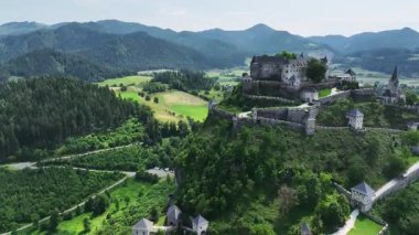 Tepedeki Hochosterwitz Kalesi 'ni, güçlendirilmiş duvarları, dramatik uçurumları, yaz renklerini, silip süpüren hava hareketlerini, tarihi dönüm noktalarını görüntüleyen sinematik dron görüntüleri.