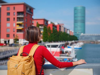Turist kadın modern Frankfurt 'u keşfediyor, çağdaş mimari, gökdelenler ve kentsel alanlarla hareketli caddelerde yürüyor, modern yan tarafların canlı atmosferinin tadını çıkarıyor..
