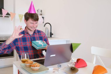 Genç bir adam doğum gününde ailesiyle görüntülü sohbet ediyor. Memleketten sevdikleriyle iletişim kurarken gülümsüyor ve seviniyor. Özel bir günü sıcaklık ve bağlantıyla kutluyor.