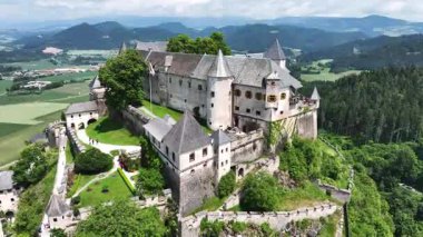 Tepedeki Hochosterwitz Kalesi 'ni, güçlendirilmiş duvarları, dramatik uçurumları, yaz renklerini, silip süpüren hava hareketlerini, tarihi dönüm noktalarını görüntüleyen sinematik dron görüntüleri.