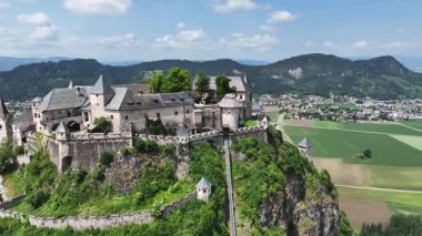 Tepedeki Hochosterwitz Kalesi 'ni, güçlendirilmiş duvarları, dramatik uçurumları, yaz renklerini, silip süpüren hava hareketlerini, tarihi dönüm noktalarını görüntüleyen sinematik dron görüntüleri.