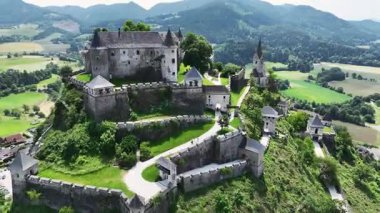 Tepedeki Hochosterwitz Kalesi 'ni, güçlendirilmiş duvarları, dramatik uçurumları, yaz renklerini, silip süpüren hava hareketlerini, tarihi dönüm noktalarını görüntüleyen sinematik dron görüntüleri.