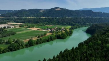 Gortina yakınlarındaki Drava nehrinin yaz drone görüntüleri, yeşil yamaçlar, durgun su, vadi kıvrımları, yumuşak akşam ışığı, barışçıl hava hareketi