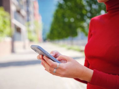 Bahar günü Frankfurt 'ta yürüyen ve elinde cep telefonu olan güzel bir kadın. Şehir yaşam tarzı konsepti. Sosyal ağları kontrol edin, mesaj ya da kitap oteli gönderin, güven ve profesyonellik yaygınlığı