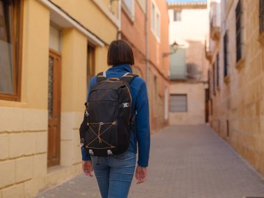 İspanya 'nın Alicante eyaletinin büyüleyici dar sokaklarında gezinen, tarihi Akdeniz mimarisi ile çevrili, barışçıl atmosfer ve kültürel ortamın tadını çıkaran genç bir kadın..