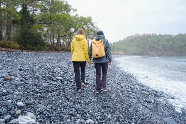 Çiftler Türk kıyı şeridini seviyor. Taşlarda oturmak, deniz dalgalarını izlemek, birlikte dinlenmek, sakin mavi suyun yanında, yumuşak kış ışığı altında romantik bir an..