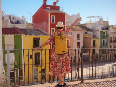 İspanyol kıyı kasabası La Vila Joiosa 'nın renkli sokaklarında gezen kadın. Güneşli kış atmosferi Akdeniz mimarisinin cazibesini ve sakin sahil yaşamını ön plana çıkarıyor.
