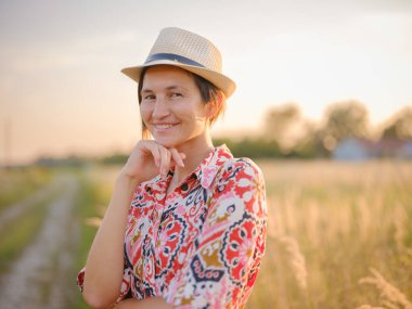 Yaz sonlarında Avrupa 'nın pitoresk alanlarında yürüyen genç bir kadın. Altın güneş ışığı, yemyeşil yemyeşil ve sakin kırsal atmosfer huzurlu bir kırsal alan yaratır..